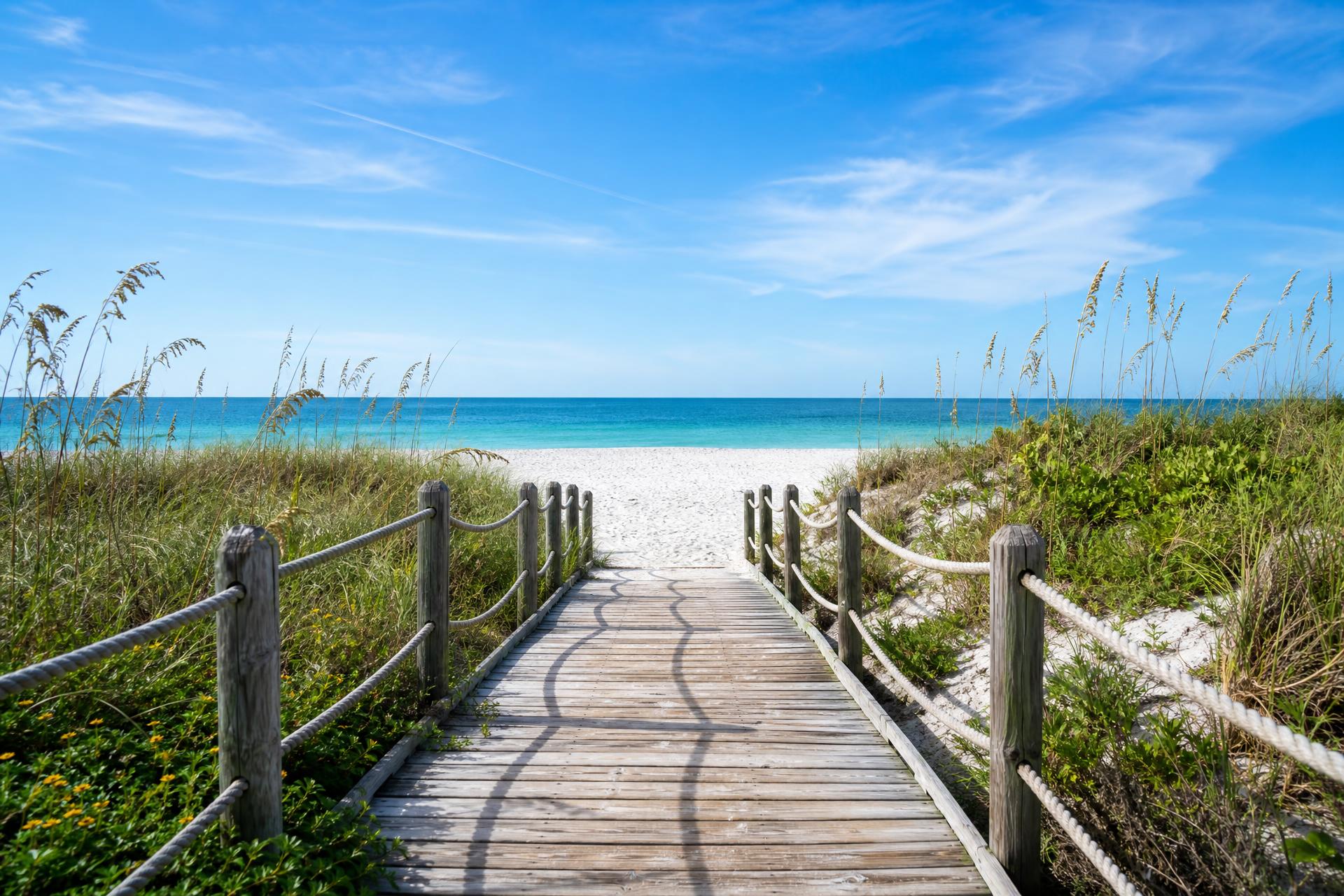 Wooden boardwalk leading through sea grass to a pristine beach