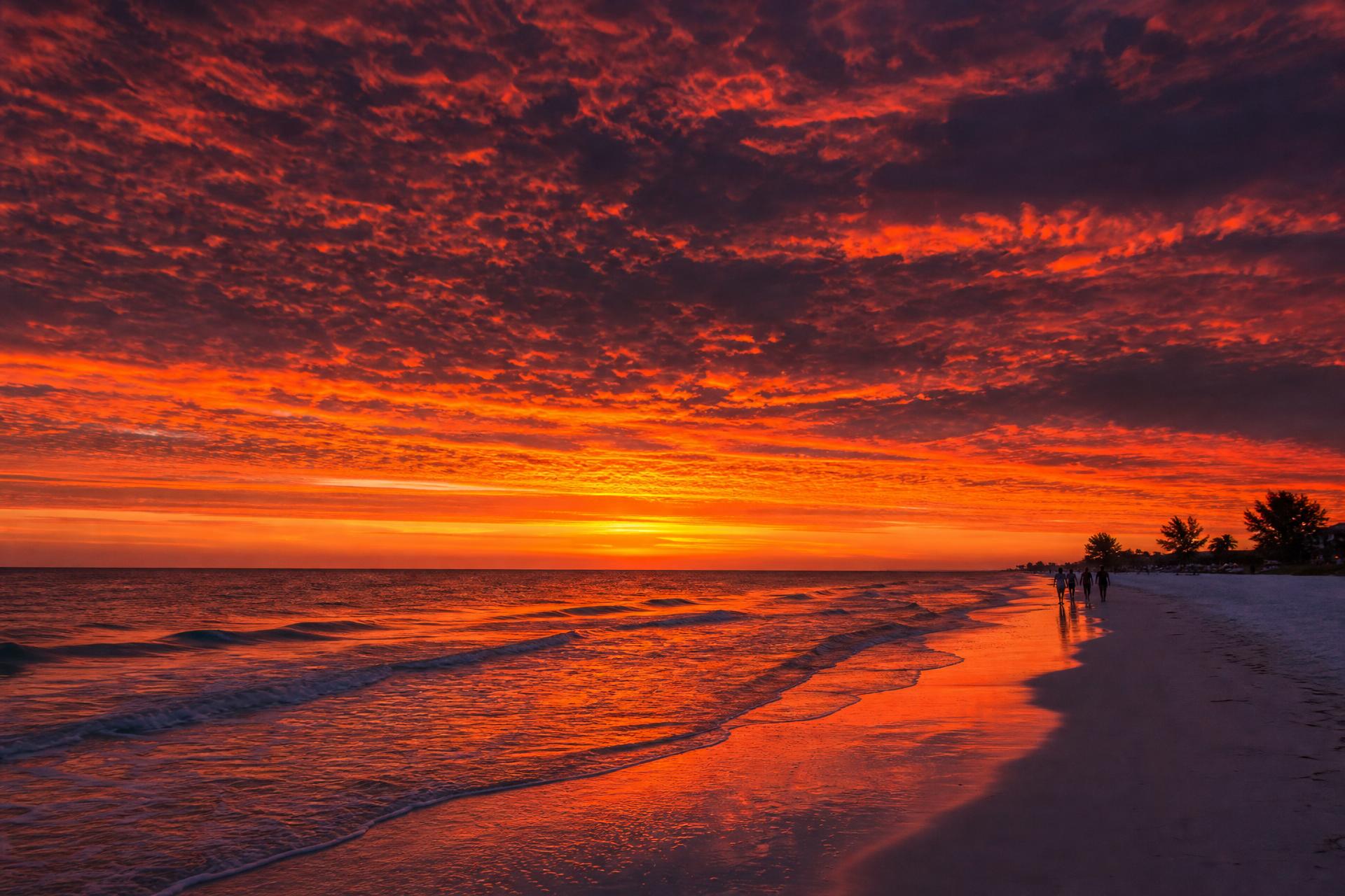 Dramatic sunset sky with silhouetted figures on Anna Maria Island beach